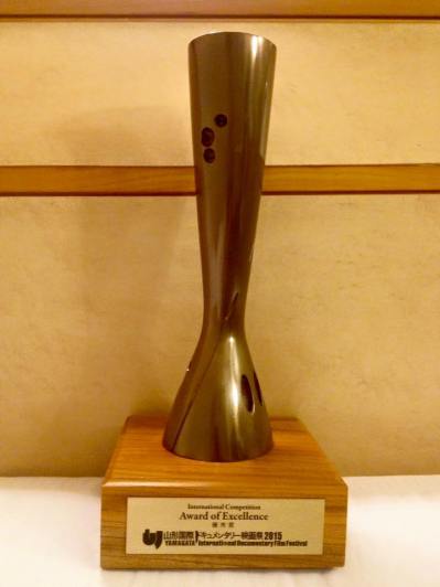 The Trophy is designed for YIDFF by sculptor Azuma Kenjiro. It is modeled after the bright yellow-green stalks of rice plants at harvest time, one of the symbols of Yamagata City and Yamagata Prefecture.
